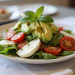 Final presentation of Caprese-Salat mit Avocado on a dining table, showcasing its vibrant colors and fresh ingredients, perfect for any meal.