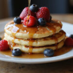 Fertige Pancakes mit Ahornsirup, garniert mit frischen Beeren, ideal für ein leckeres Frühstück.