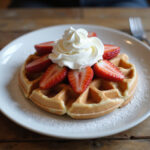 Fertige Waffeln mit Sahne und frischen Erdbeeren, ideal für ein leckeres Frühstück.